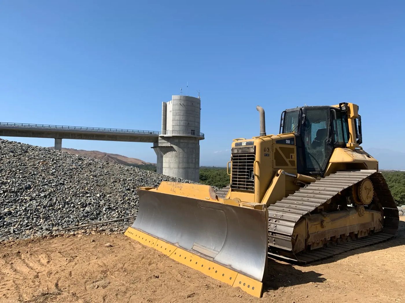 CAT track dozer at an earthwork site with a concrete tower behind it