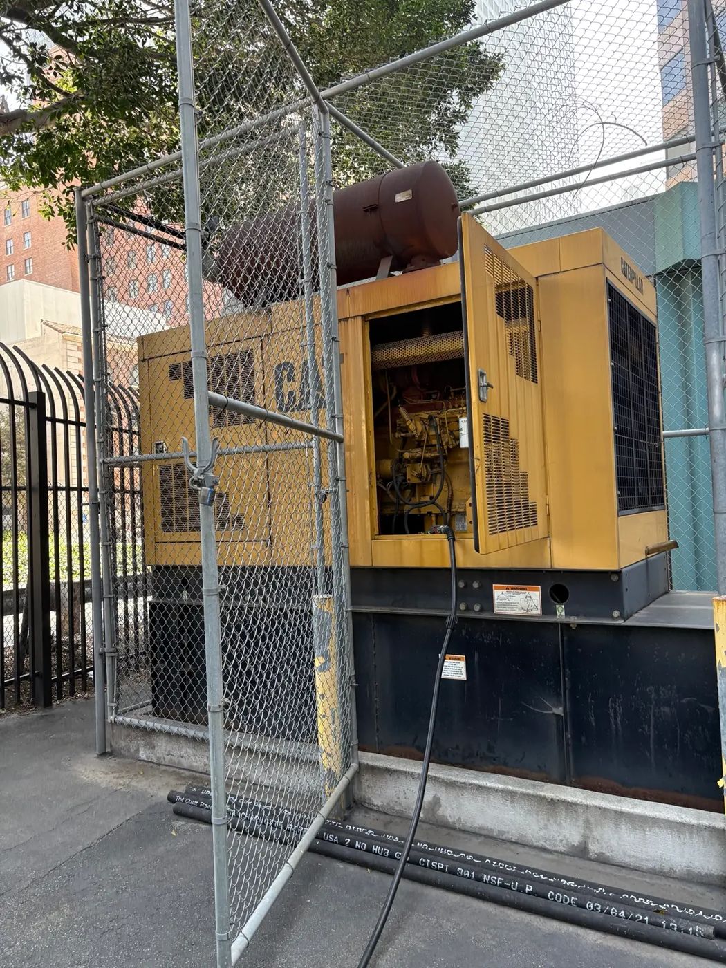 Standby diesel generator with an open service door and a fuel hose connected